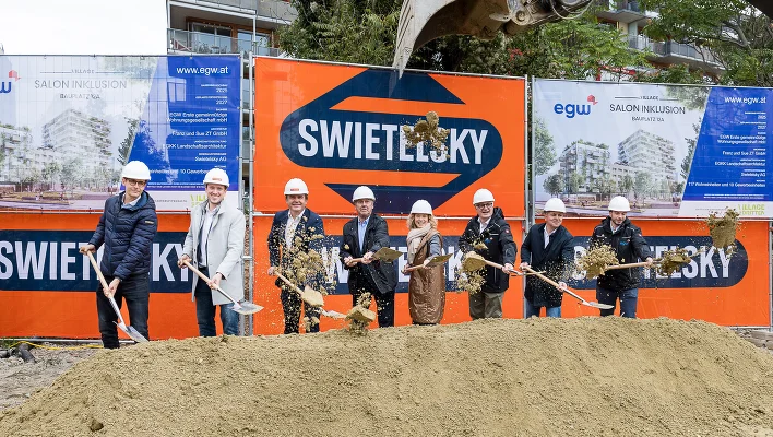 Personen mit Spaten vor der Baustelle