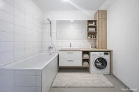 Badezimmer mit Badewanne, Unterschrank, Waschmaschine, Stauraum und Spiegel