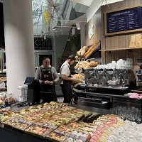 Vitrine mit Gebäck, Kaffeemaschine und 2 Mitarbeiter