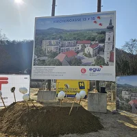 Bautafeln mit Sandhaufen, Spaten, Helmen