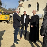 Menschen mit Baugeräten im Hintergrund und Teil der Kirche